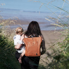 Woman walking towards the beach carrying a child with the Saunton Oak backpack on her back