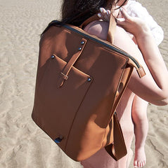 Woman on the beach carrying the Saunton backpack in oak over her shoulder